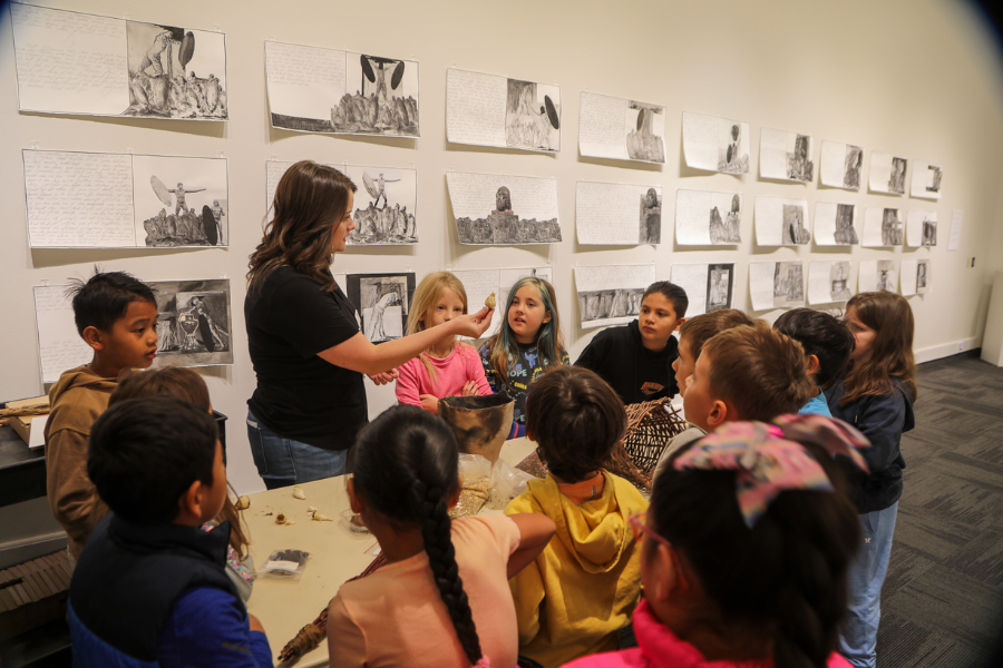 Children gathered around a teacher holding up an item