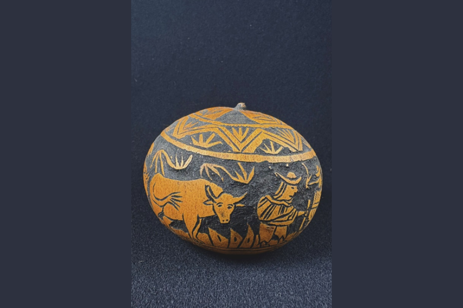 A carved circular gourd, with carvings of a cow and farmer