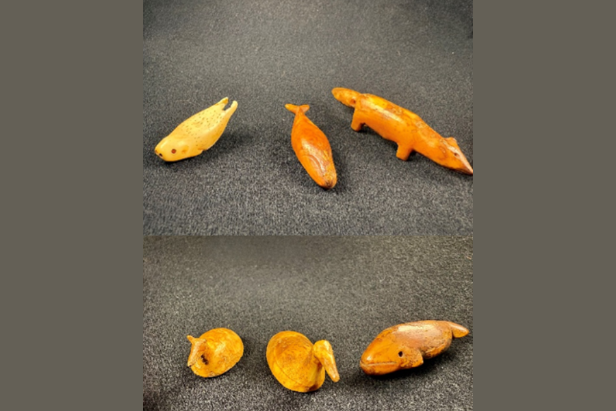 Two images (from different angles) of beads in the shapes of an otter, sperm whale, fox, deer, moose, and humpback whale 