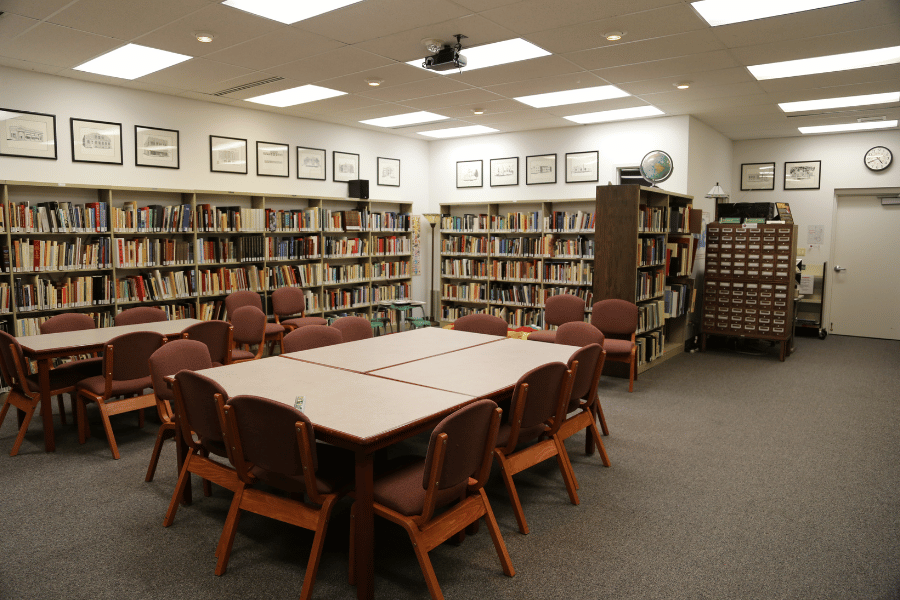 Image of tables in the center of a room, surrounded by library book shelves